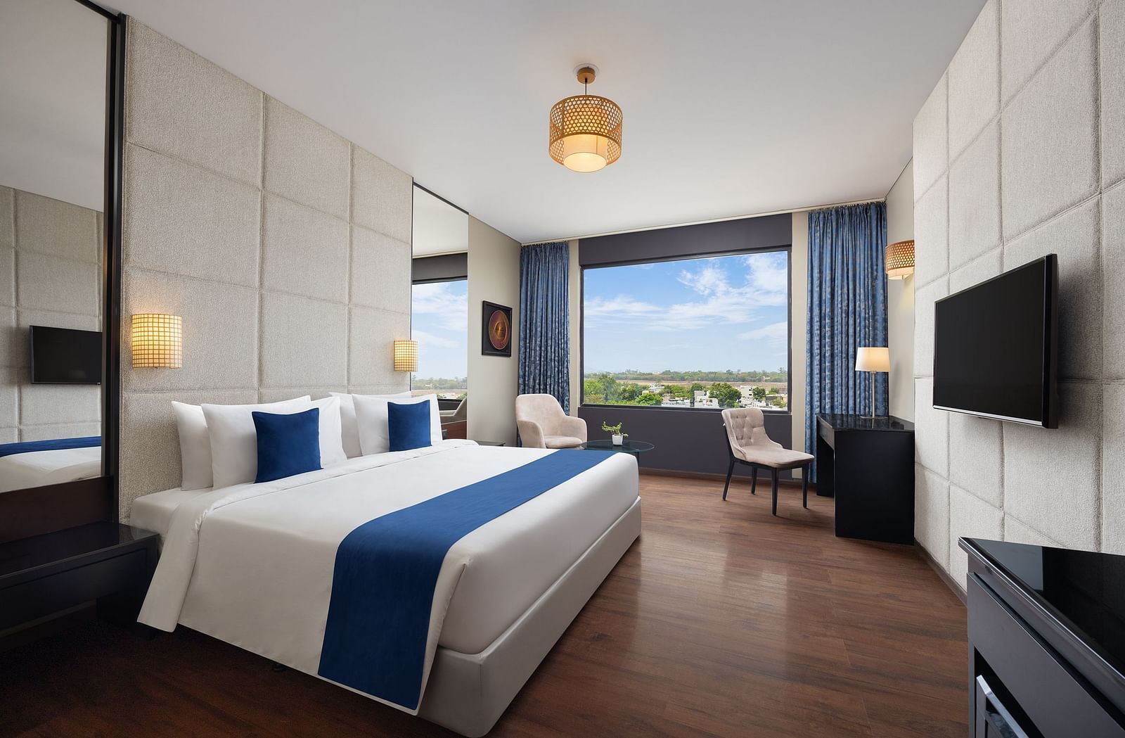 Deluxe king room at Essentia Luxury Hotel, Indore with a double bed and a television