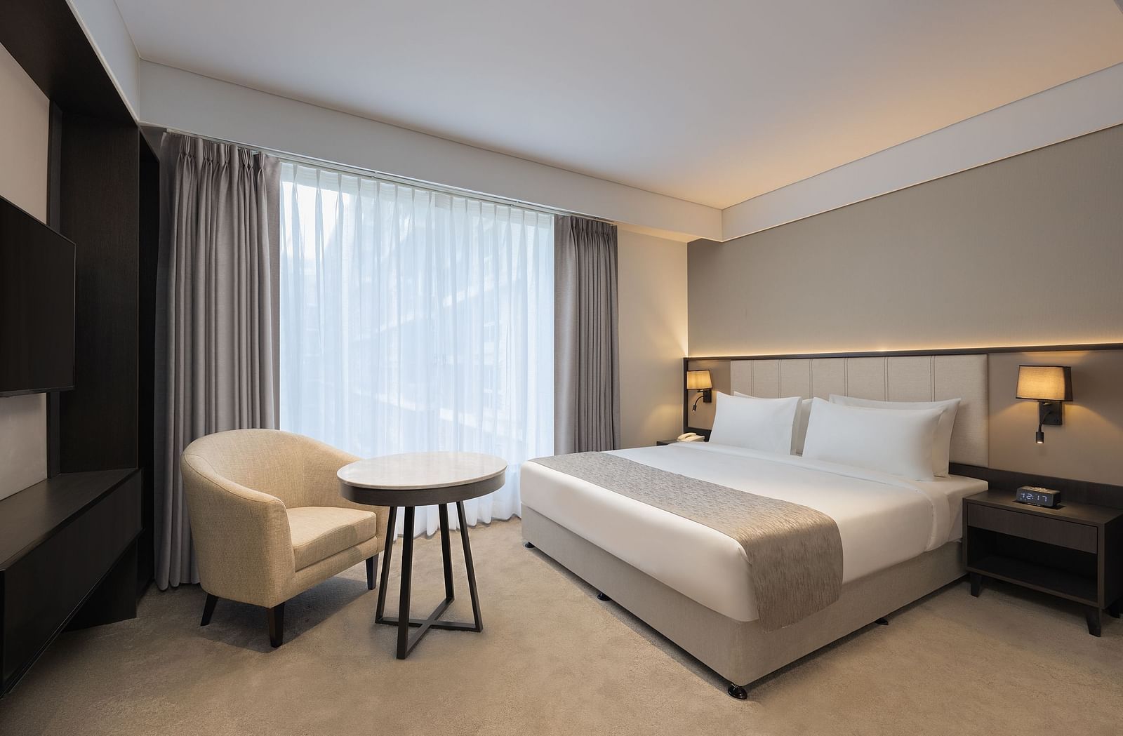 Deluxe King Room with a king size bed and a comfortable chair beside a large window at Essentia Premiere, Pune. 