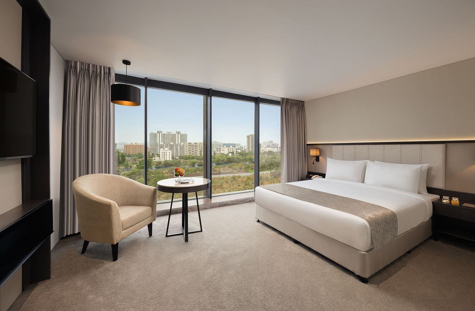  Premier Room with a king size bed and a sofa beside a large window at Essentia Premiere, Pune.