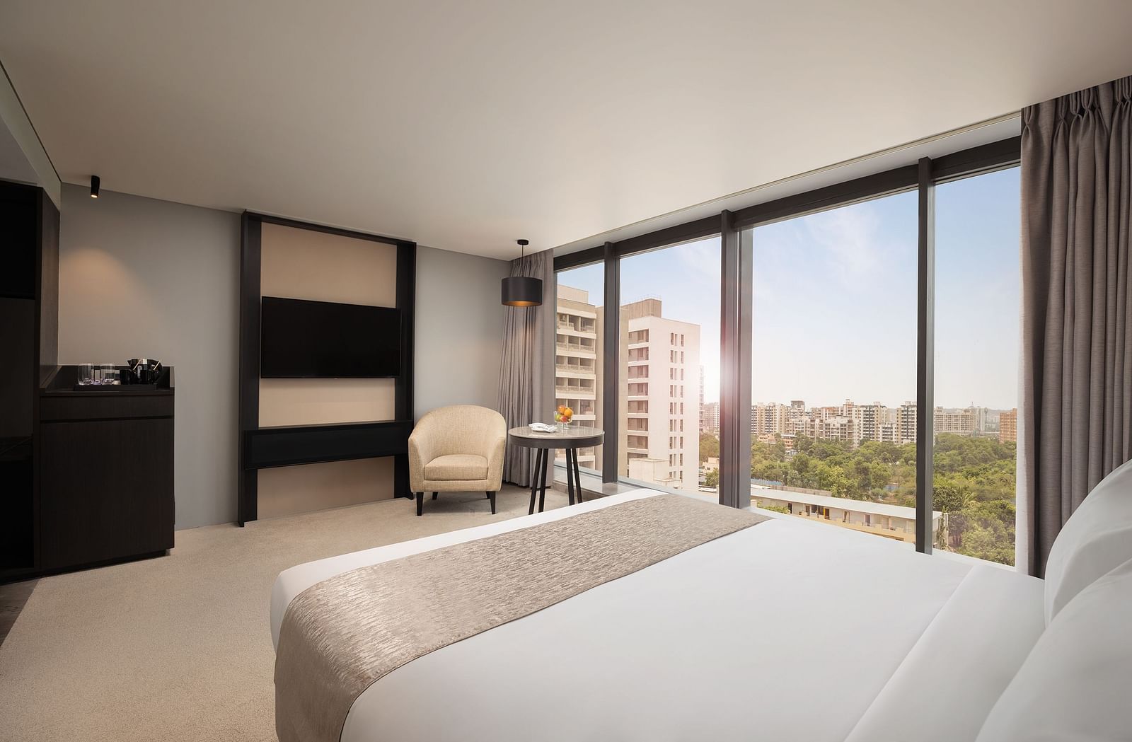 Premier Room with a king size bed and a view through a large window at Essentia Premiere, Pune.
