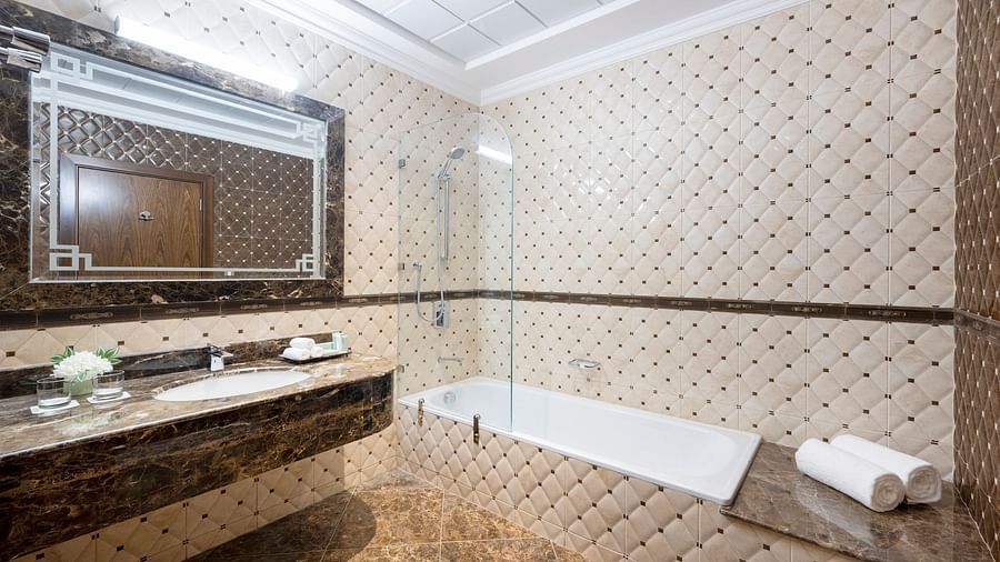 An overview of the bathroom with sink area and bathtub in view inside one of the rooms - La Maison Hotel, Doha
