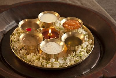A golden tray with small bowls and items, arranged on a cloth - Shreyas Retreat