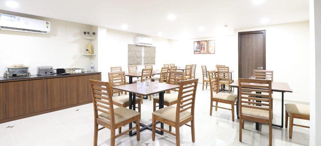 Corner view of the restaurant in a brightly-lit indoor space at Pravasa Stay, Ahmedabad (Alba Premier).
