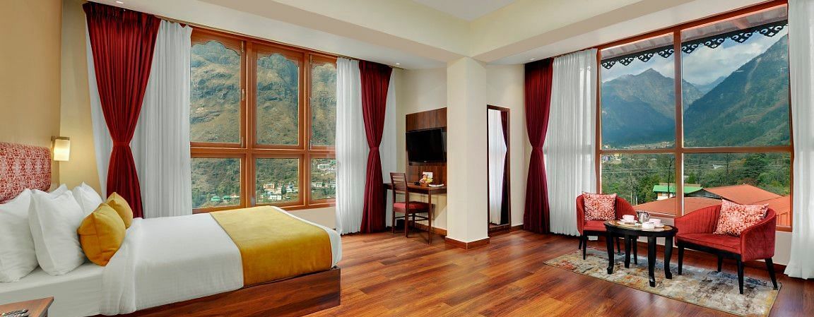 Shot of the luxurious suite at our hotel with a king size bed, wooden flooring, a cosy  seating area  | Yashshree Lachung