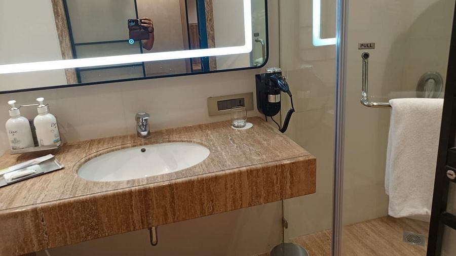 A well-lit bathroom in an executive room at Mirage Hotel, featuring the sink area and a glass partition separating the shower space.