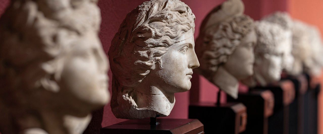 A row of ancient Roman busts displayed on a shelf.