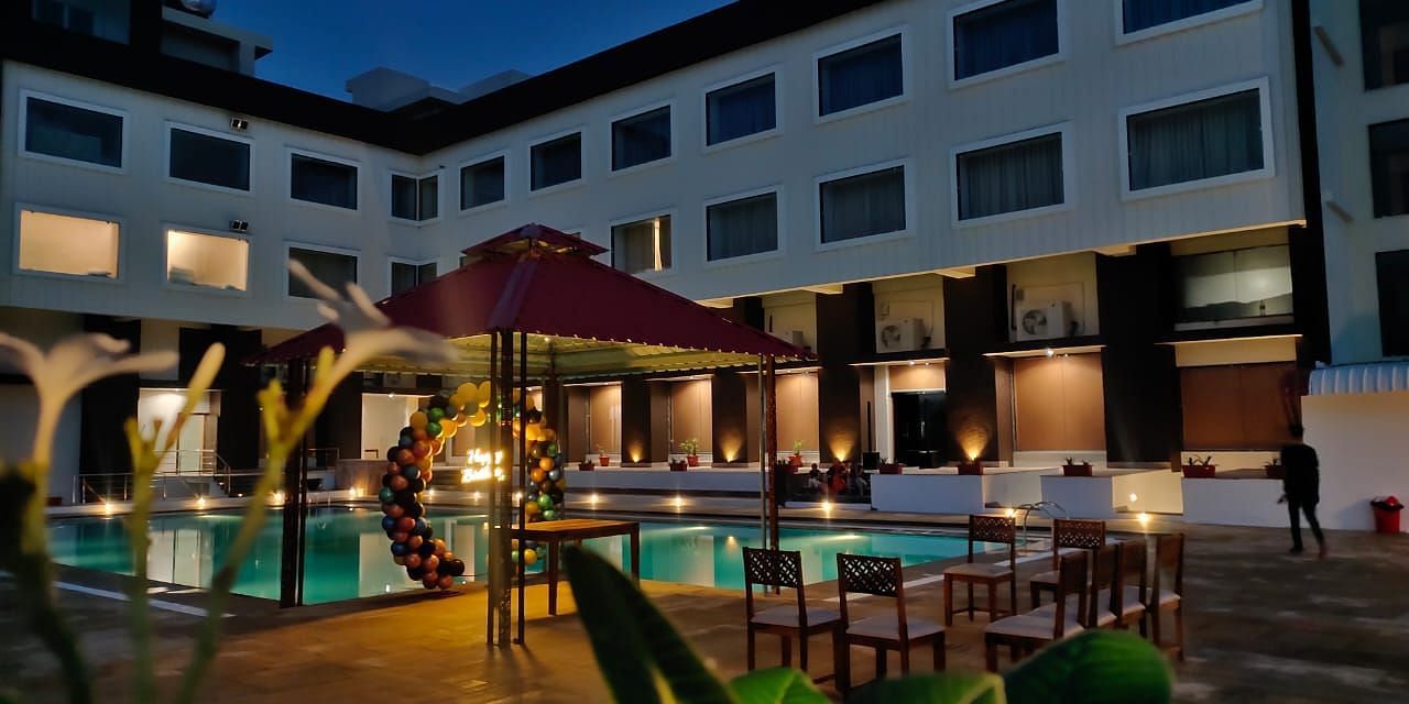 An evening view of a resort building with illuminated windows surrounding a swimming pool - Bamboo Saa Mulberry Resort, Pushkar