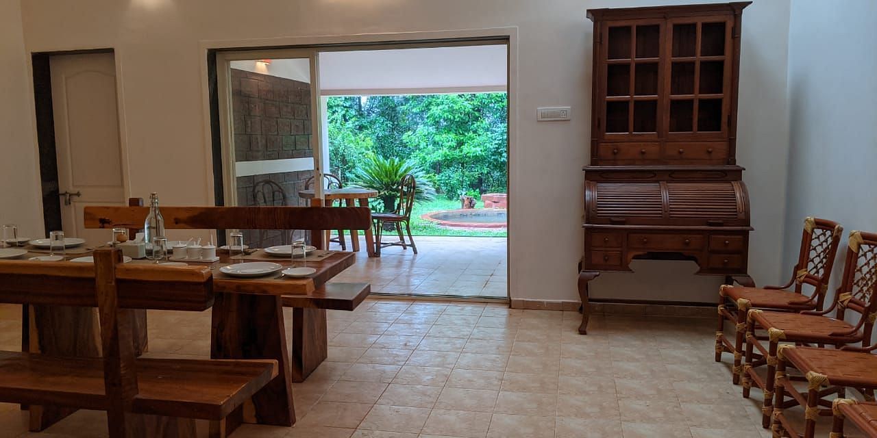Dining area with wooden furniture and an open view of greenery at The Conservancy Bungalow.