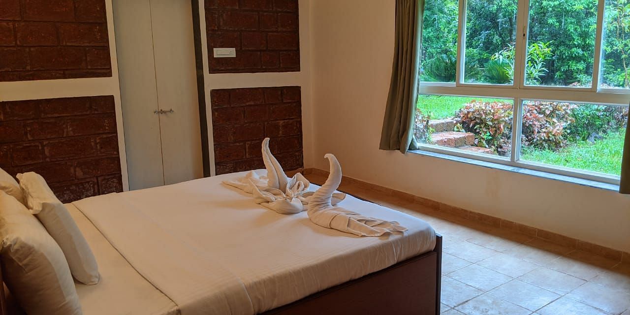 A well-lit bedroom with a large bed, window, and neatly folded towels at The Conservancy Bungalow.