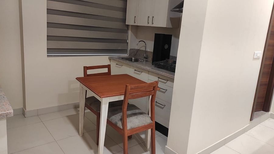 A space featuring a dining table and 2 chairs, a sink, a cooking stove and a chimney - A M Suites