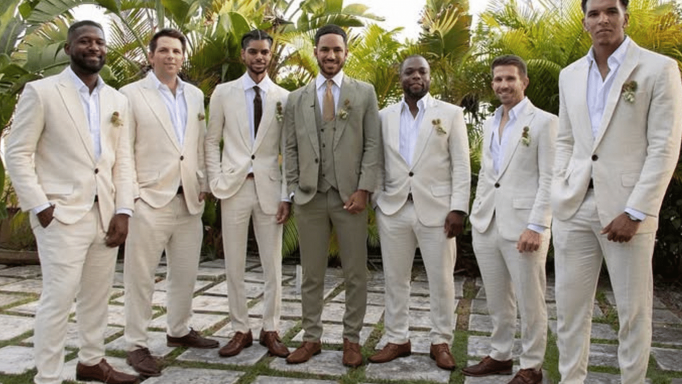 A group of groomsmen in beige suits standing outdoors on a stone pathway with greenery in the background | A Stone's Throw Away