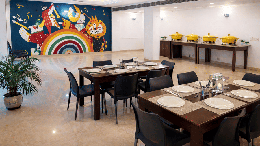An in-house dining area with table seating, buffet counter, and wall artwork at EMBLEM - Arjun Marg, Golf Course Road, Gurgaon.