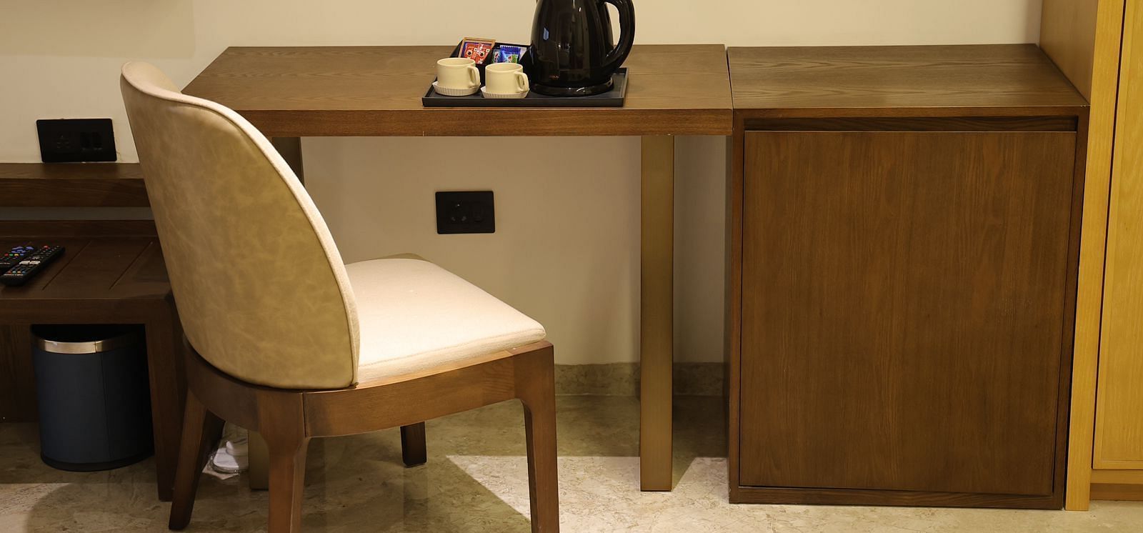 A well appointed writing desk area at Lords Eco inn Jamnagar Maheshwari Nagar with a chair and tea coffee making facilities.