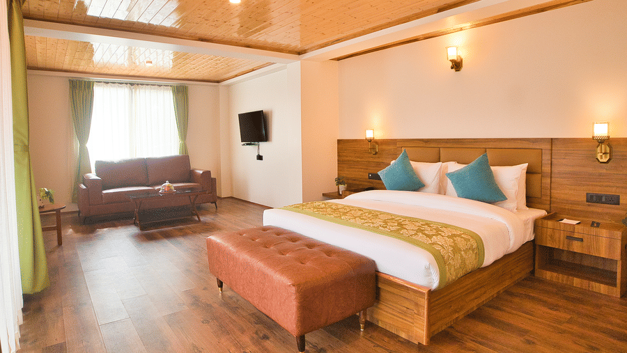 Elegant suite at Voyage Songfum Retreat featuring a king-size bed, cozy seating area with a leather sofa, warm wooden interiors, and soft natural lighting.