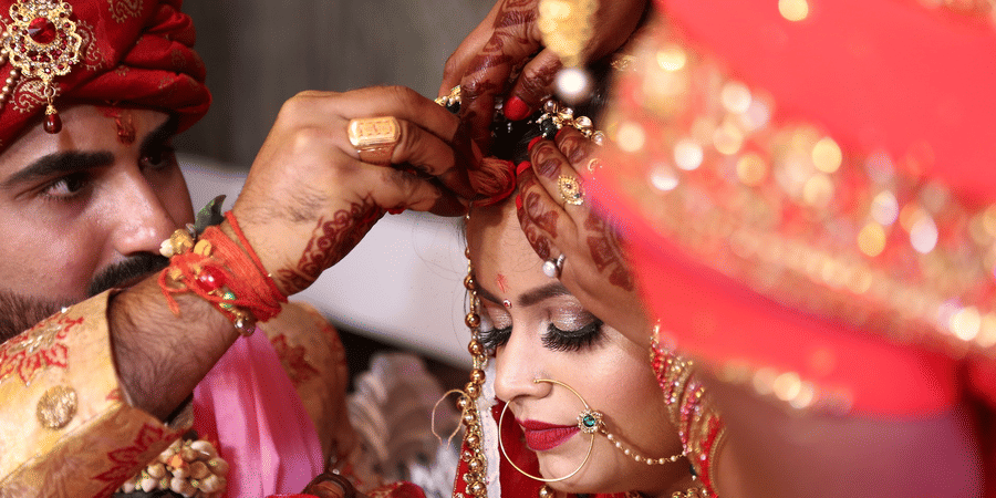 husband putting vermilion on his wife during their marriage ceremony