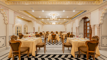 a well arrnaged dining setup in our indoor restaurant with black and white tiles and elegant furnishings - Brij Castle, Jaipur