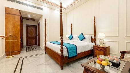 corner view image of the room with a double bed and the wooden door at the entrance crossing the wardrobe - Brij Castle, Jaipur