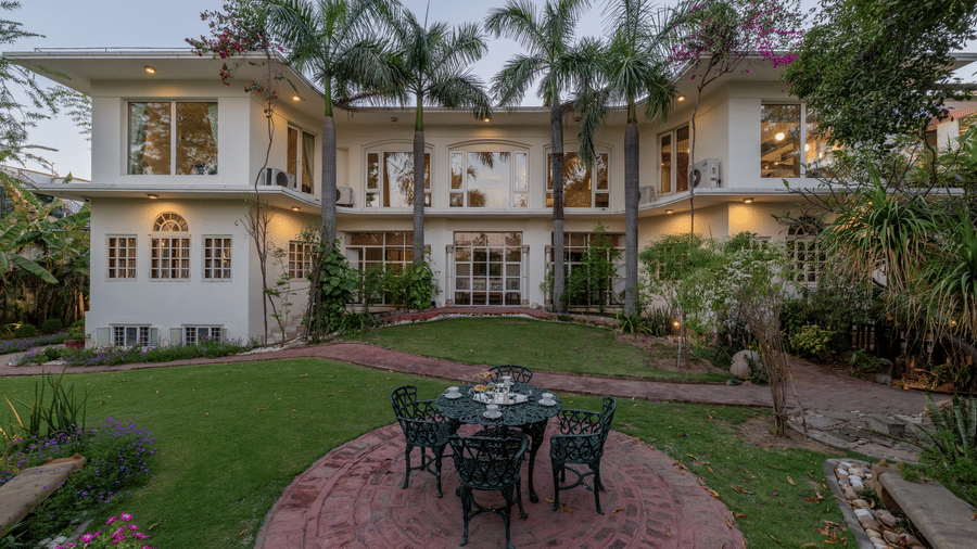 An elegant heritage homestay with a creme-coloured facade and lush green lawns with outdoor seating - Barwara Kothi, Jaipur