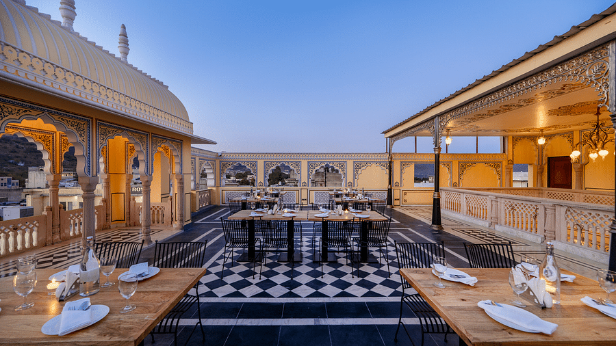 side view image of the dining area at our roof top with two dining tables at the side and the cover pathways with warm lighting in the corner13-March-2025