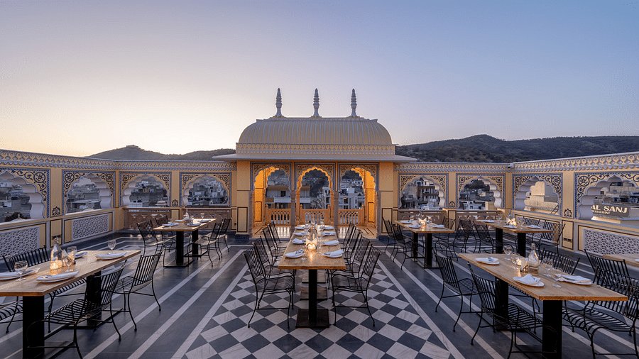 a roof top dining setup with beautiful views of the surrounding mountains and the early sunset - Brij Castle, Jaipur