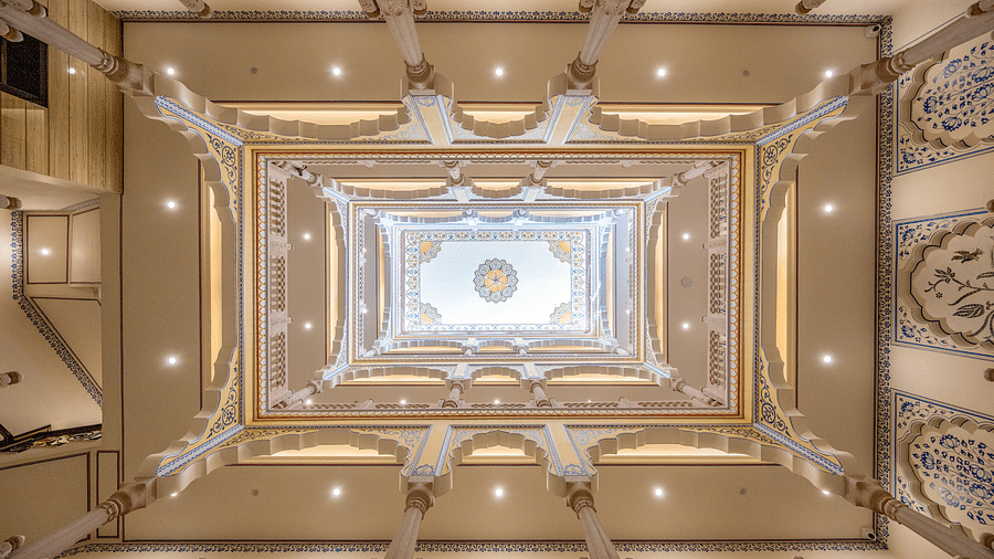 a beautiful atrium above the lobby of our hotel going four levels up with intricate paintings on the wall - Brij Castle, Jaipur