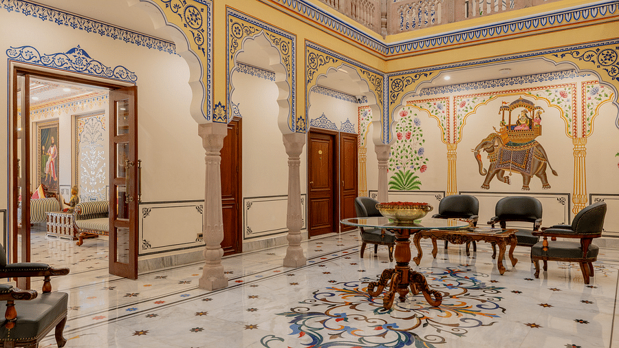 an expansive lobby at our hotel with colourful patters engraved on the white tiles and a door opening to the the reception area - Brij Castle, Jaipur