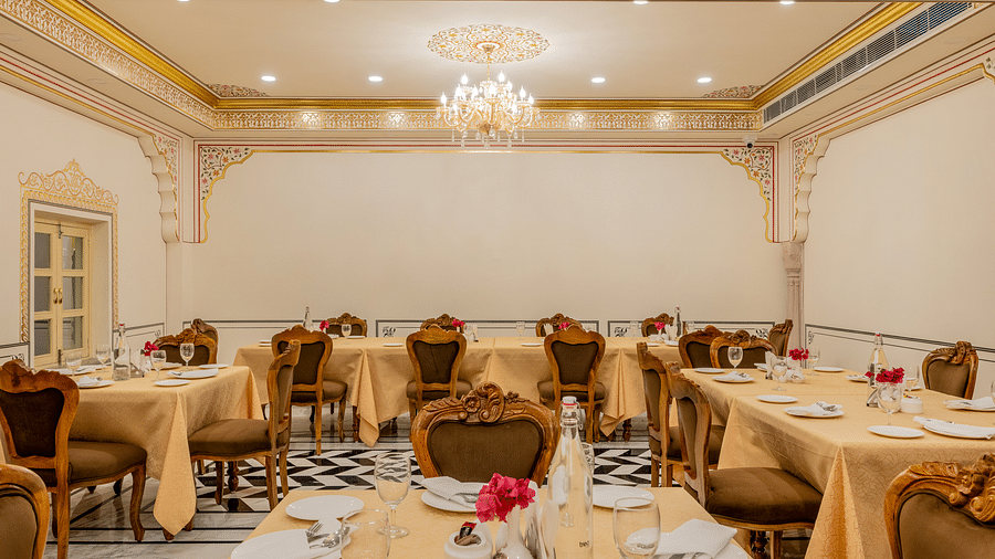 well set dining tables with beige coloured table cloth spread across - Brij Castle, Jaipur