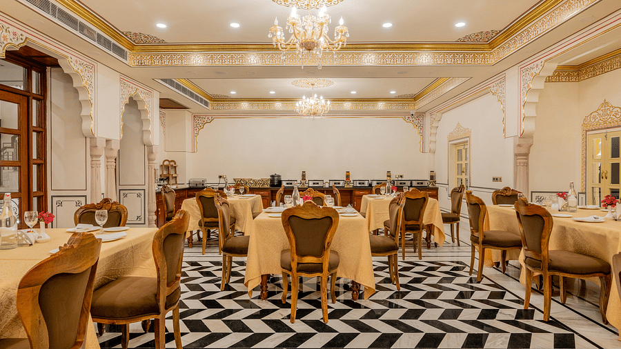 full view image of the dining area with arched hallways with beautiful wooden doors and golden borders in the ceiling - Brij Castle, Jaipur