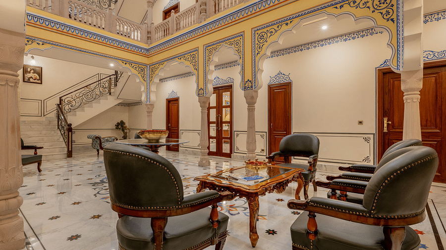 corner view image of the lobby featuring a common seating area along with a white coloured staircase right opposite to it leading to the first level - Brij Castle, Jaipur