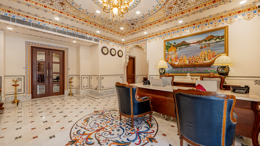 back side of the reception area with a wooden door in the corner opening to the lobby area - Brij Castle, Jaipur