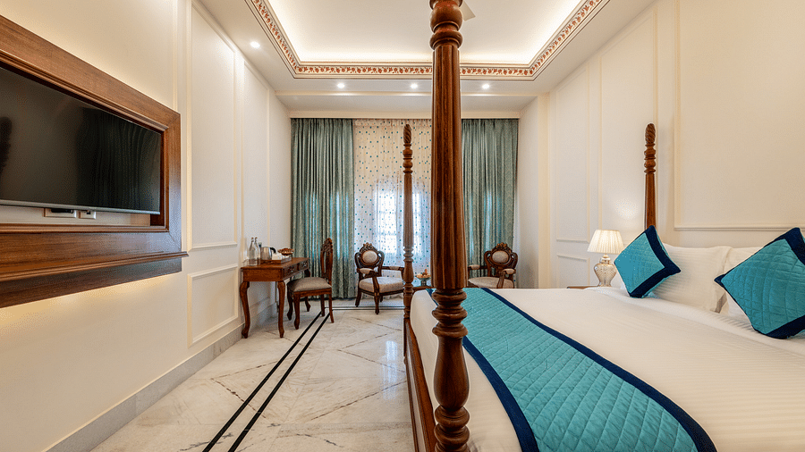a luxurious and well ventilated bedroom featuring a double bed along with a common seating area at the far end of the room - Brij Castle, Jaipur