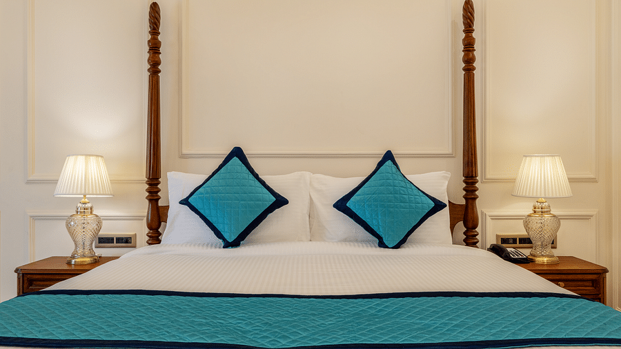 close up image of a double bed with two blue cushions kept over it - Brij Castle, Jaipur