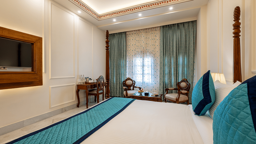 a luxurious bedroom with ample lighting featuring a double bed along with wall mounted television - Brij Castle, Jaipur