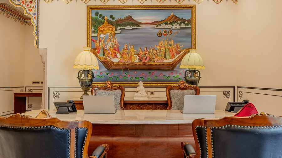 the reception area with the table and two laptops kept over it along with a beautiful painting behind it - Brij Castle, Jaipur
