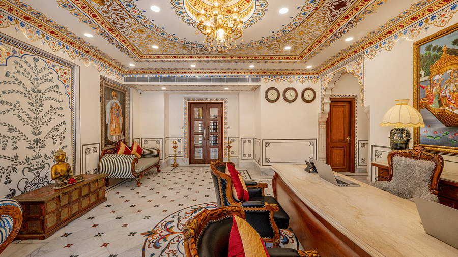 full view image of the reception lobby with a beautiful chandelier hanging with a beautiful tree mastiff painted in the background - Brij Castle, Jaipur