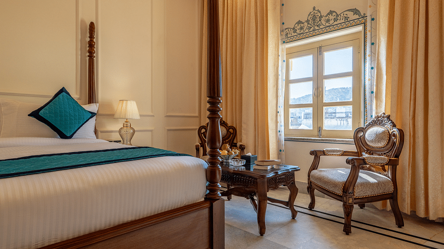 a bedroom with intricate paintings on the wall over the window with a common seating area in front of it - Brij Castle, Jaipur