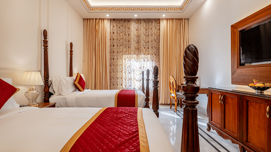 a bedroom with two single beds with a sleek and traditional modern interiors with a wall mounted television in front of it - Brij Castle, Jaipur