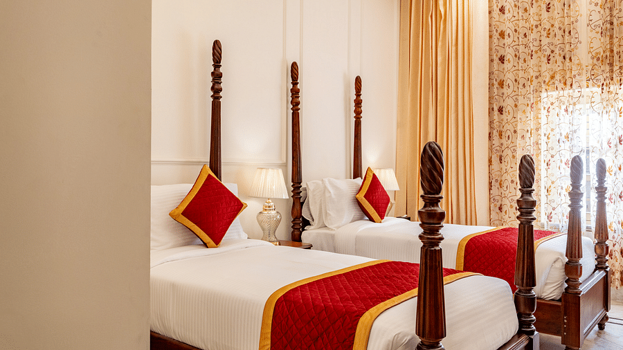 a bedroom with two single beds with plenty of natural light coming from the window beside it - Brij Castle, Jaipur