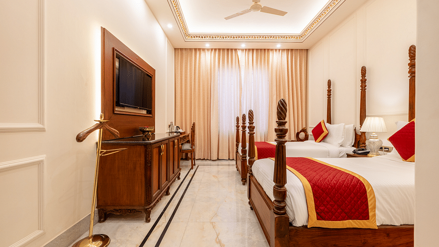 a room with a twin bed facing towards the wall mounted television with a coat hanger beside it - Brij Castle, Jaipur