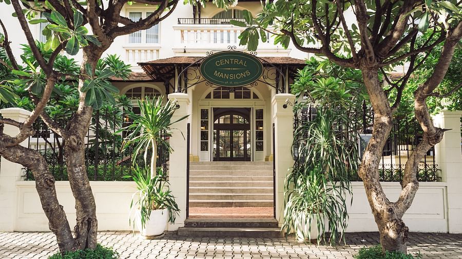 A close-up of an entrance with a staircase, surrounded by trees | Central Mansions, Phnom Penh