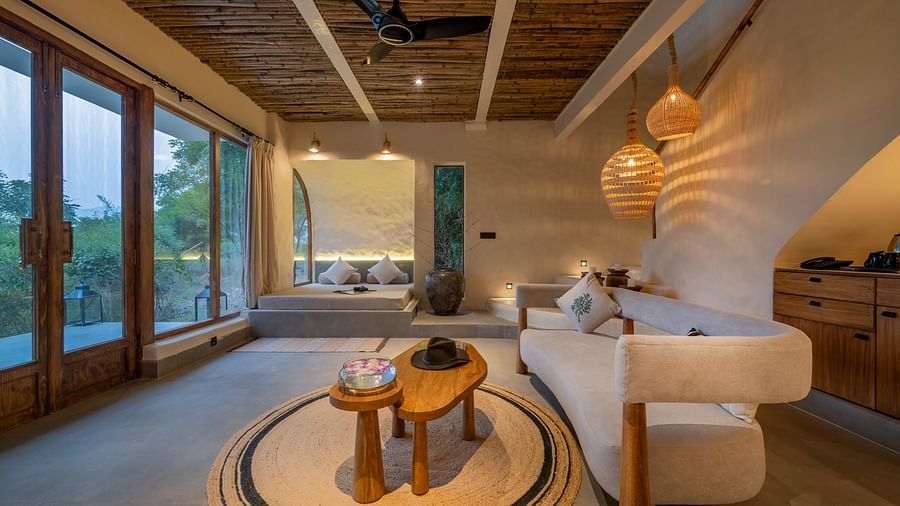 Close-up of a bedside area with a warm lamp, cushioned seating, and natural decor.