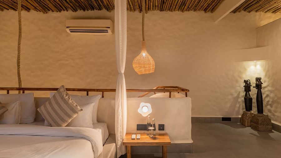 Cosy bedroom with a bedside lamp, natural decor, and cushioned seating along the wall.