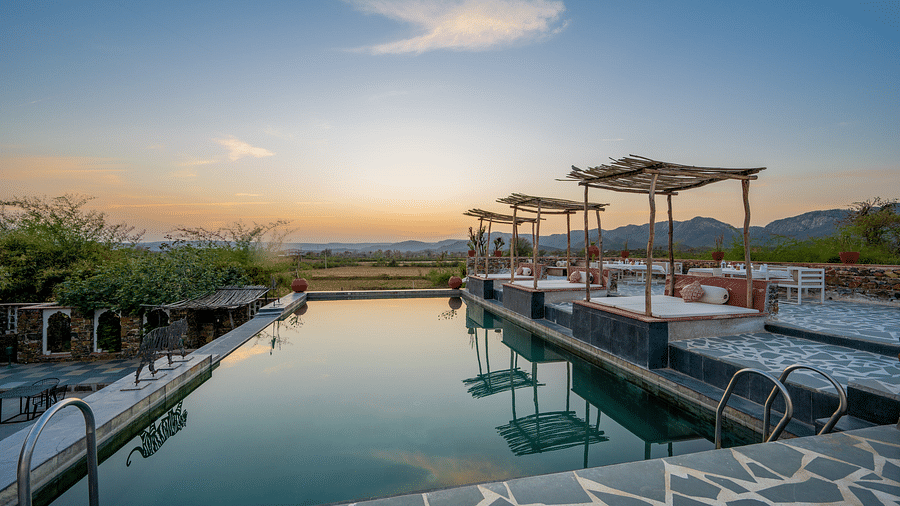 An image of the swimming pool with seating arrangement near it in the open - Utsav Camp Sariska