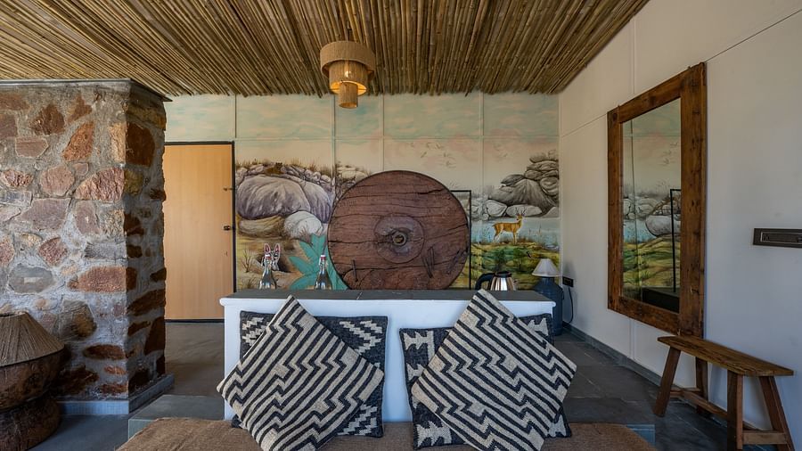 An image of a room with queen sizes bed, decorative items, and wall paintings - Utsav Camp Sariska
