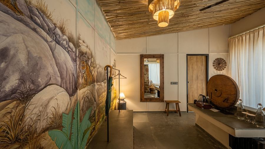 An image of a room with wall paintings, chandelier, ceiling fan, and decorative items - Utsav Camp Sariska