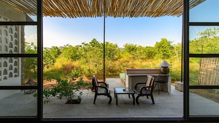 An image of an outdoor seating over looked from an expansive glass door - Utsav Camp Sariska