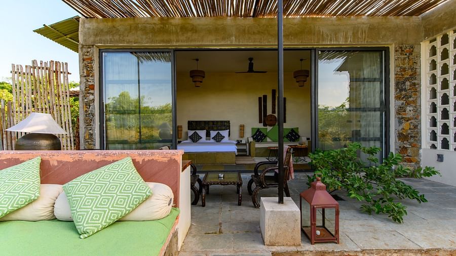 An image of a room with an expansive glass door leading to the outdoor area - Utsav Camp Sariska