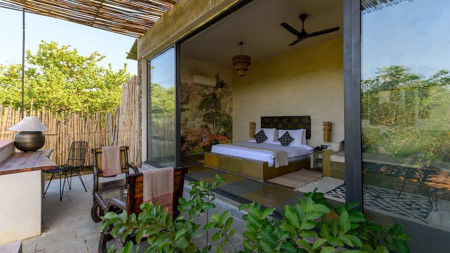 An image of a room with an expansive glass door leading to the outdoor area - Utsav Camp Sariska