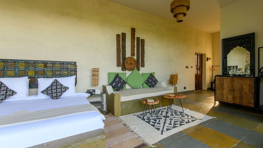 An image of a room with a queen size bed, chandelier, ceiling fan and other decorative items - Utsav Camp Sariska