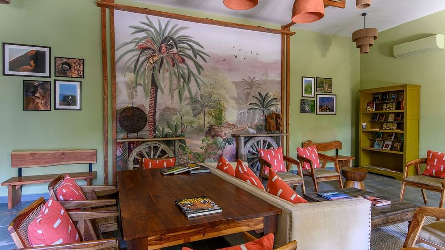 An image of a room with sofa set, center table wall hangings and paintings with minimal decorations - Utsav Camp Sariska